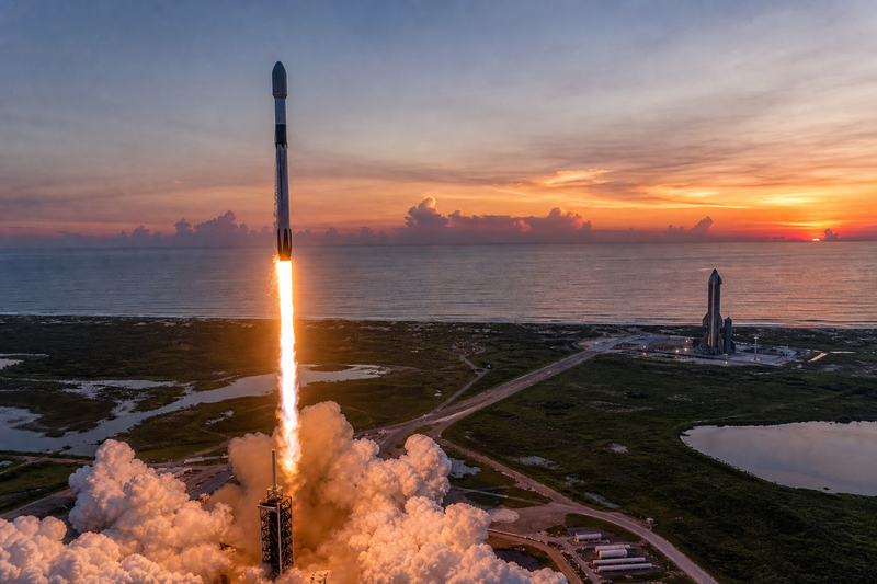 SpaceX Falcon 9 launching from Florida coast while Starship stands nearby at dusk