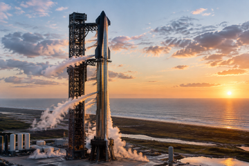 Starship rocket on launch pad at dawn with condensation plumes, ready for orbital test.