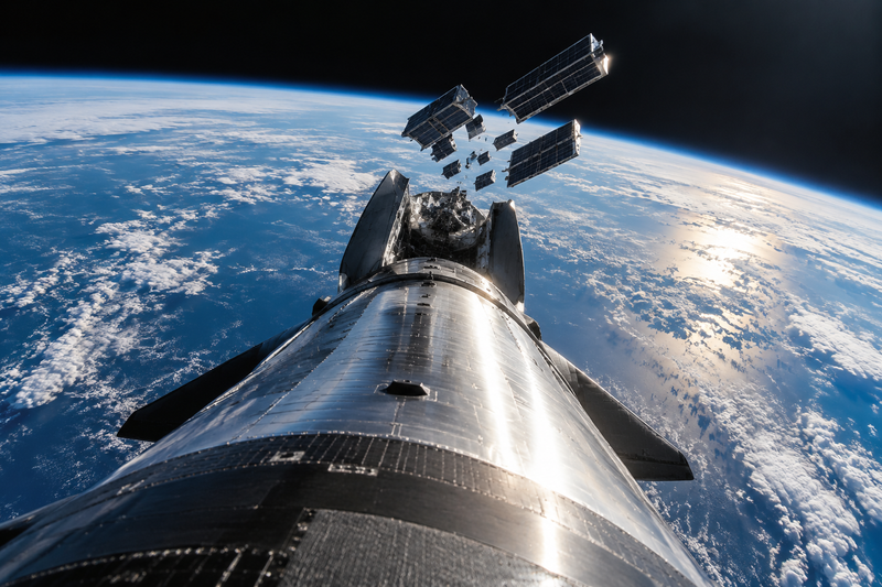 SpaceX Starship upper stage deploying Starlink satellites in orbit above Earth.