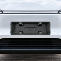 A black metal license plate frame mounted on the front bumper of a white vehicle, shown against a clean outdoor background.