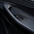 Single-window-switch door panel with carbon-weave covers around the switch and two door-release control areas.
