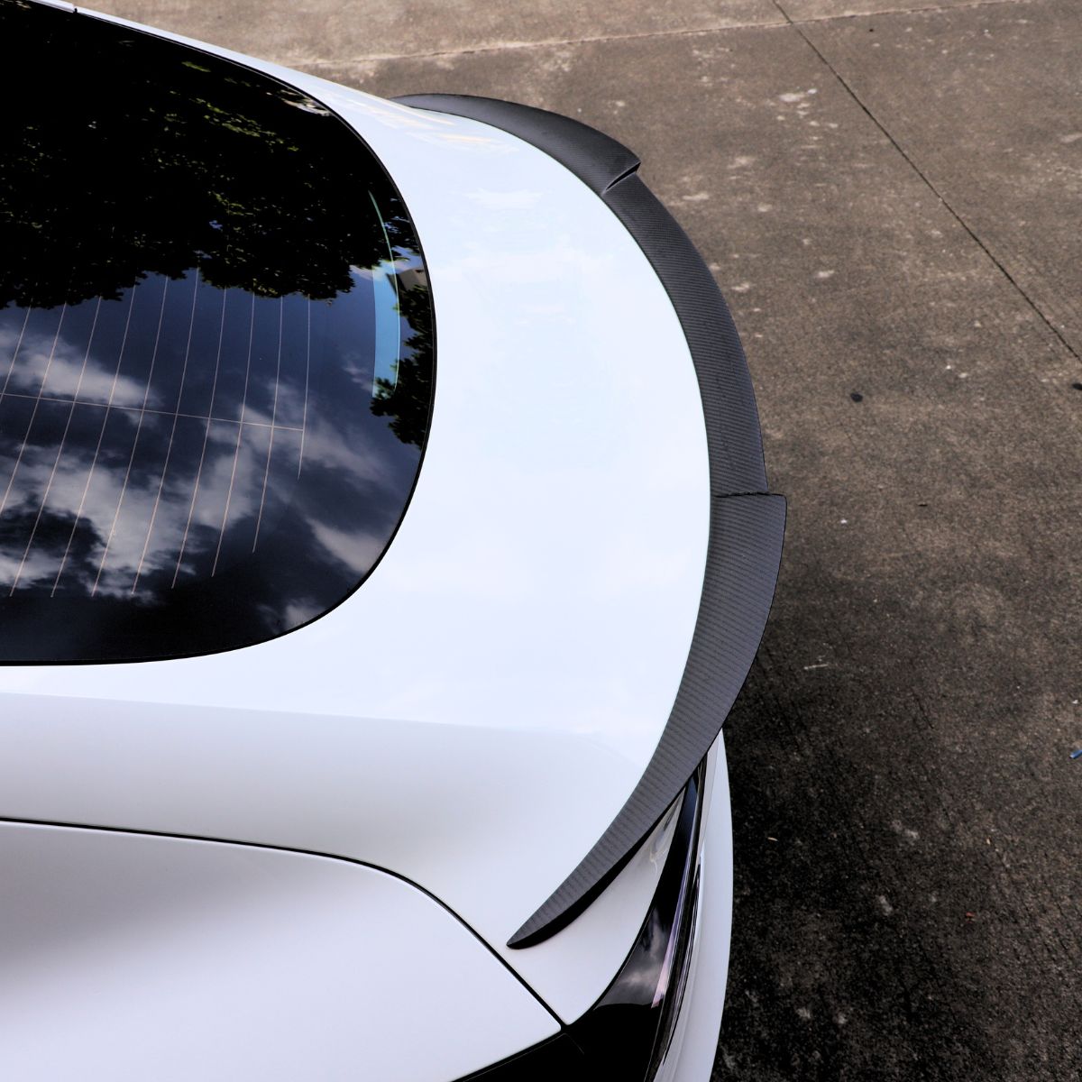 Carbon fiber spoiler following the rear edge of a Tesla Model 3 Highland trunk