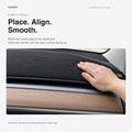 A hand smooths the black flannel mat on a legacy Tesla dashboard, with the wood trim and cabin air outlet below.