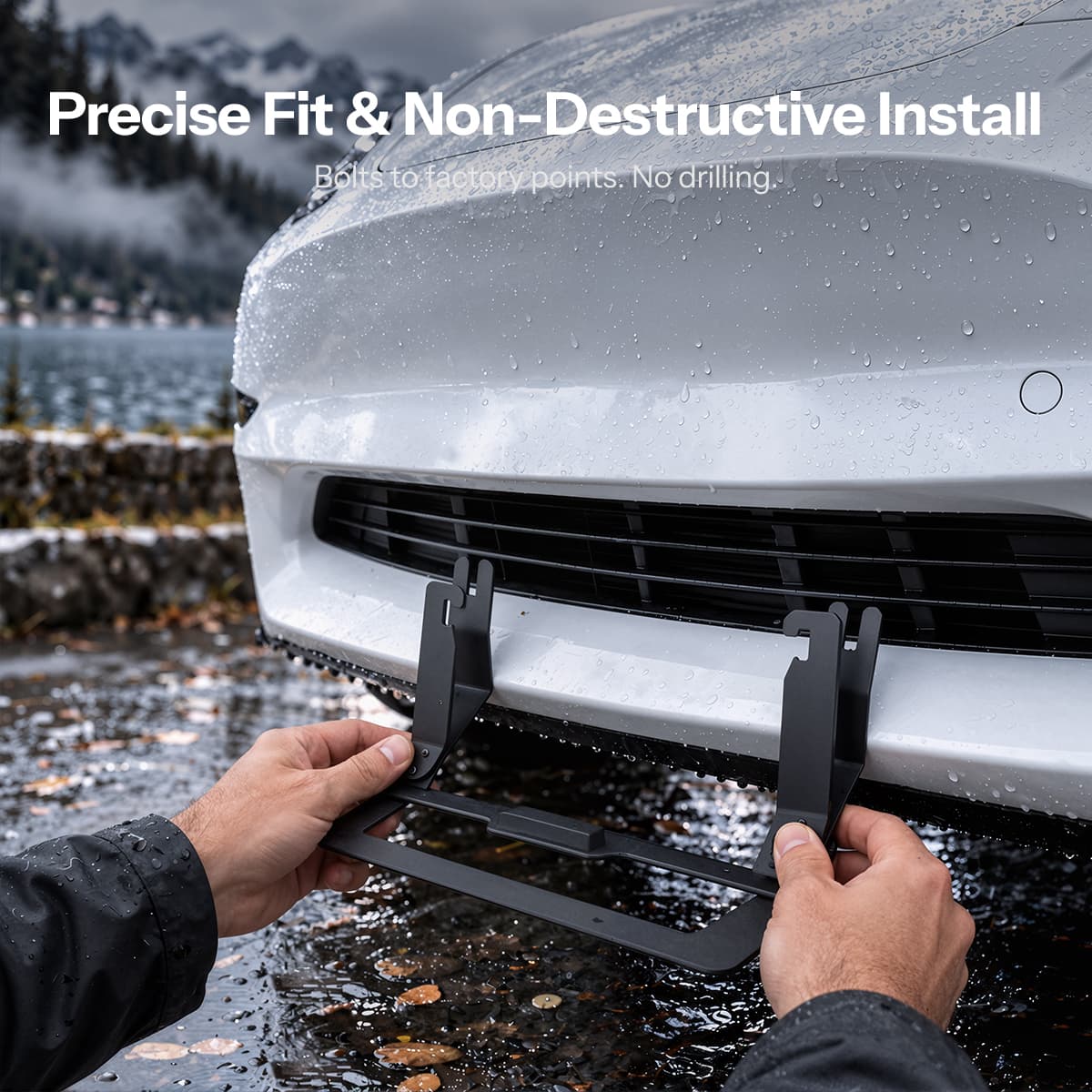Hands aligning a black plate bracket at the lower grille of a white Model 3.