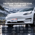 White Model 3 with a short front license plate mounted above the lower grille on a wet mountain road.