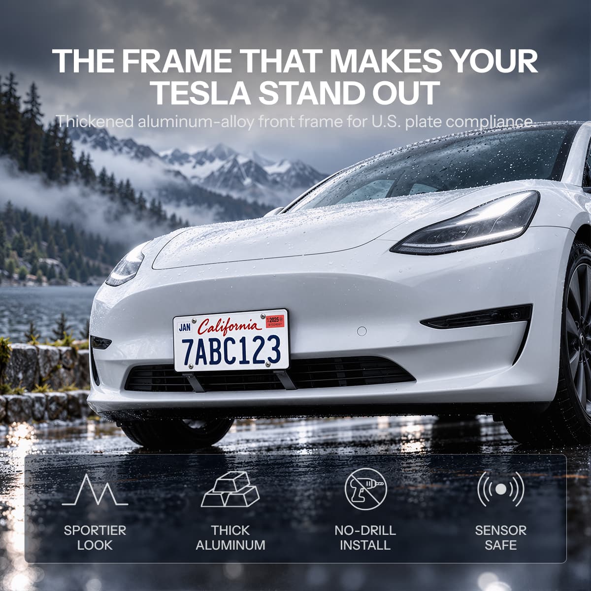 White Model 3 with a short front license plate mounted above the lower grille on a wet mountain road.