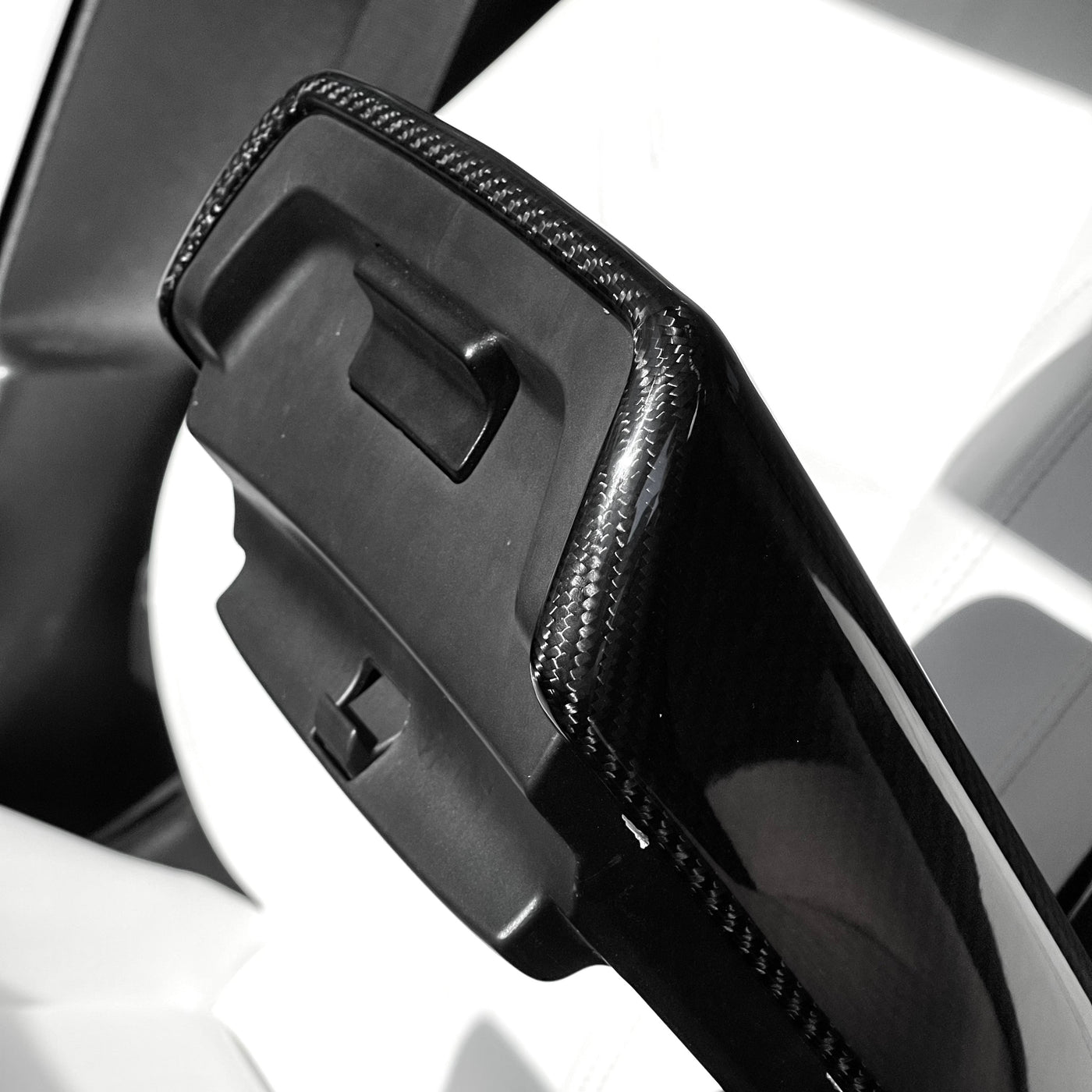 Underside view of the molded carbon fiber armrest cover showing the center-console release opening