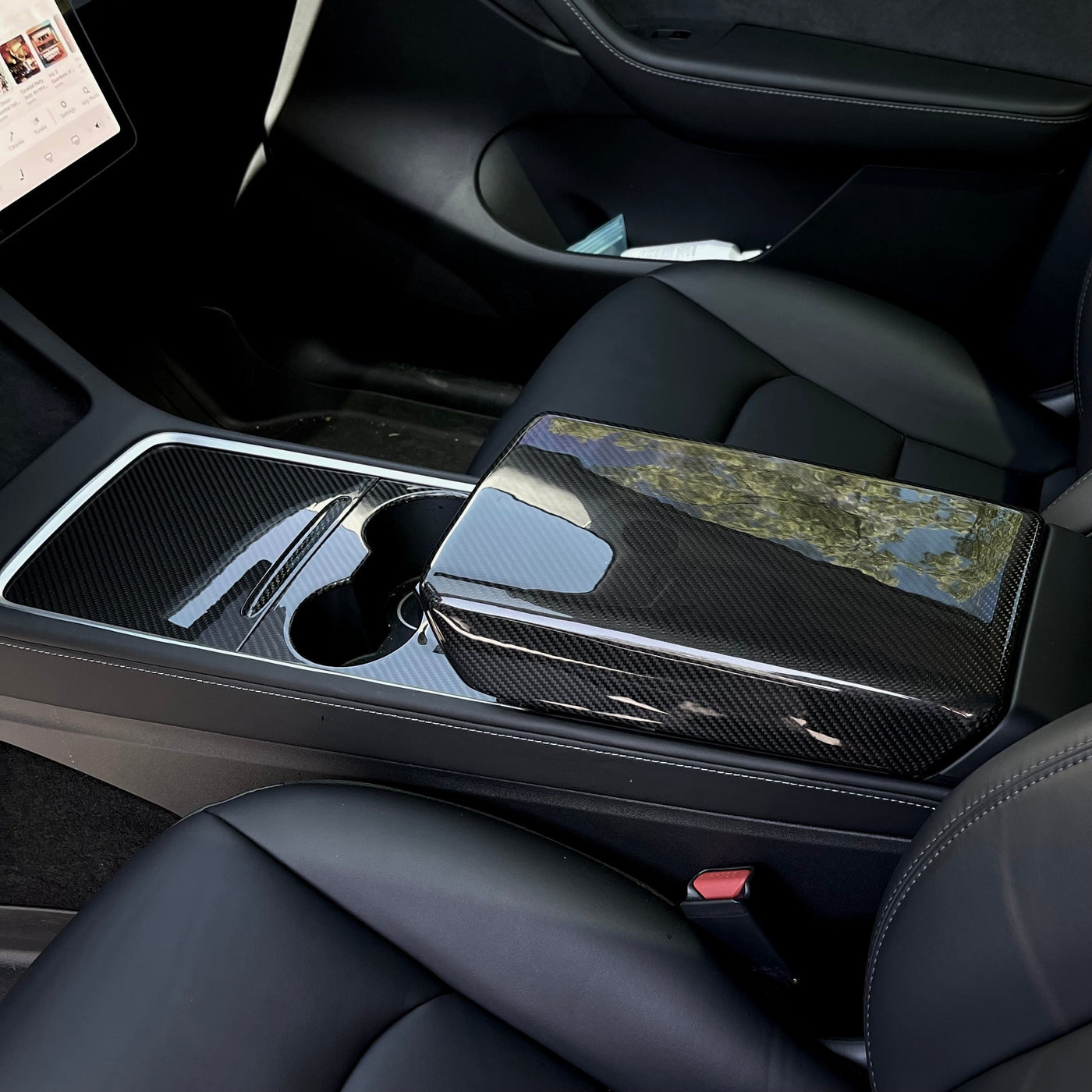 Glossy carbon fiber armrest shell installed over the center-console lid