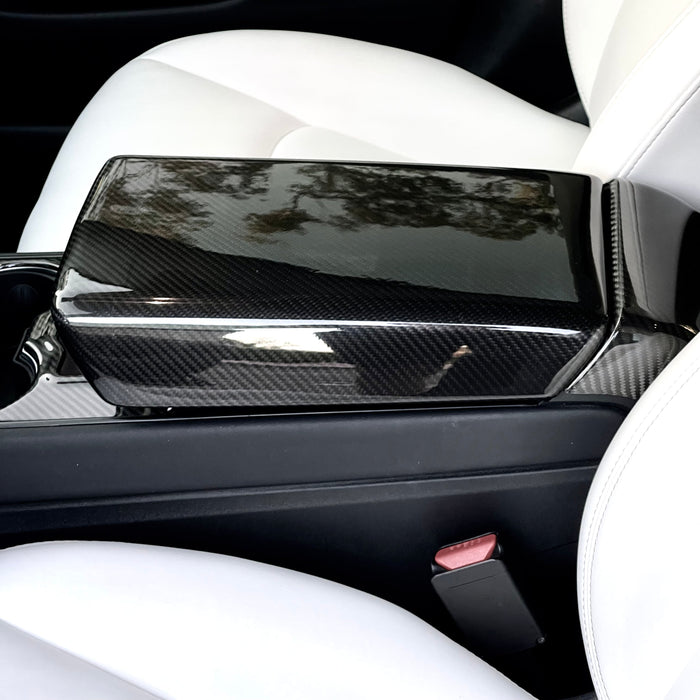 Glossy real carbon fiber center armrest cover installed in a Tesla Model 3 or Model Y