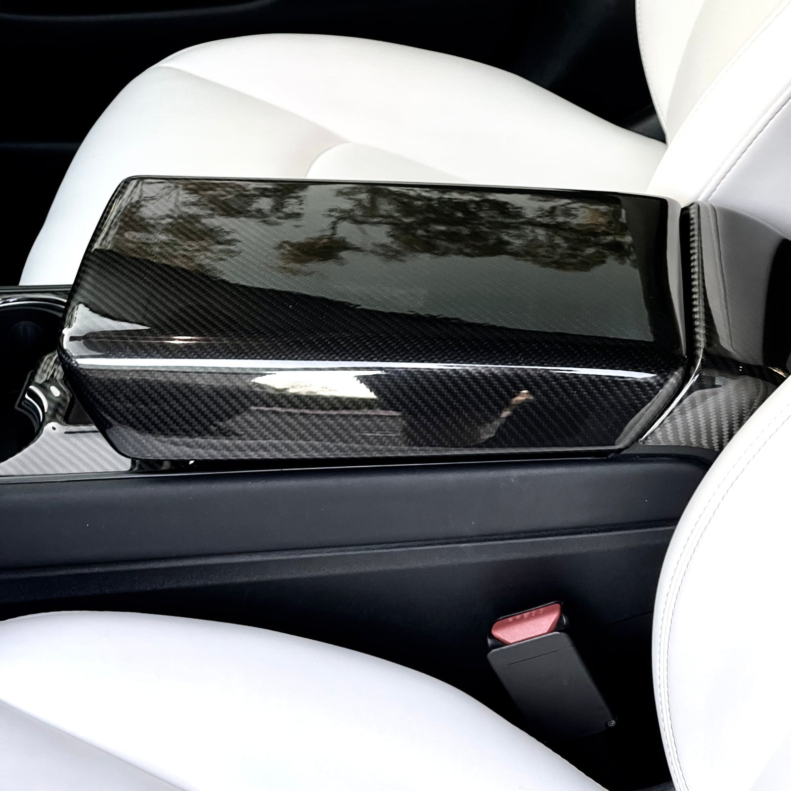 Glossy real carbon fiber center armrest cover installed in a Tesla Model 3 or Model Y
